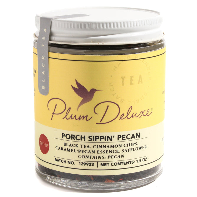 A clear jar of Plum Deluxe Porch Sippin Pecan Praline Tea with a yellow label featuring a bird logo and ingredients. This fragrant loose leaf tea has a gray lid and is tagged as black tea.
