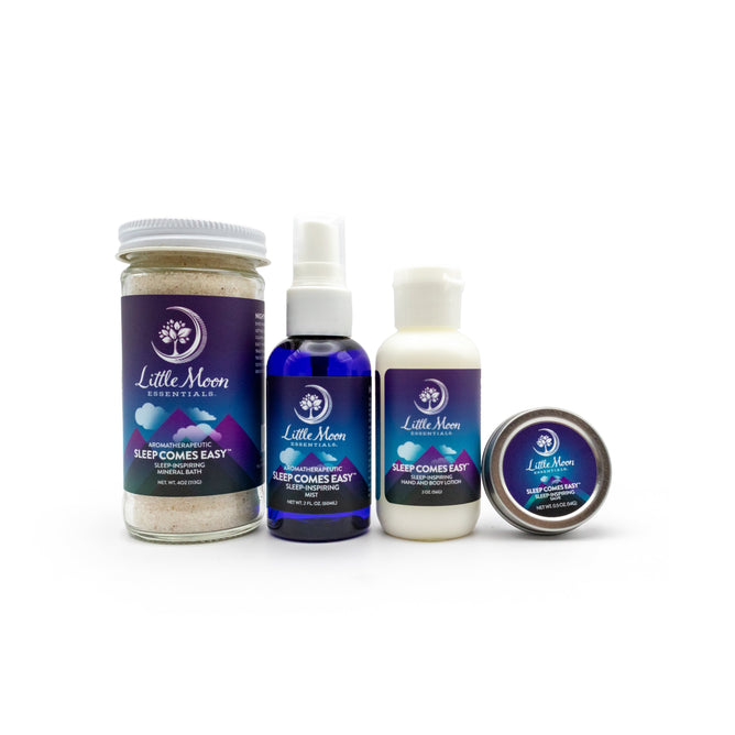 The Sleep Comes Easy Gift Set by Little Moon Essentials is displayed on a white background, featuring calming products: mineral bath salts in a jar, a blue spray bottle, a lotion bottle, and a small tin. Each has a purple Sleep Comes Easy label to promote restful sleep.