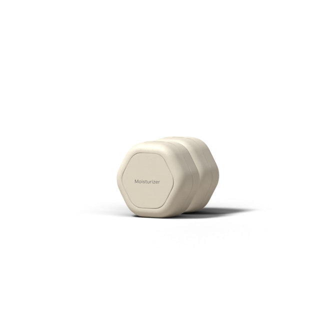 A hexagonal, off-white Cadence Skincare Duo Travel Container, TSA-compliant and labeled Moisturizer, sits centered on a white surface with a soft shadow against a minimal background.