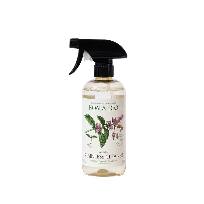 A clear spray bottle of Koala Eco Stainless Steel Cleaner - Peppermint with a black trigger nozzle, botanical illustrations, and green text. This eco-friendly cleaner is biodegradable, plant-based, and has a fresh peppermint scent.