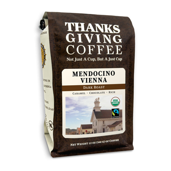 The Thanksgiving Coffee Organic Mendocino Vienna Dark Roast features organic dark roast coffee with B Corporation certification, offering caramel, chocolate, and rich flavors. Its packaging depicts a quaint building under a blue sky, showcasing its commitment to Fair Trade coffee.