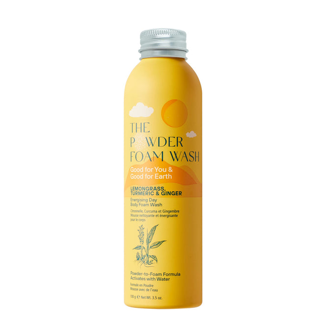 A cylindrical bottle with a silver cap labeled Energising Body Foam Wash by The Powder Shampoo is adorned with lemongrass and turmeric illustrations, enriched with papaya enzyme. It features lemongrass essential oil, turmeric, and ginger while promoting eco-friendliness.