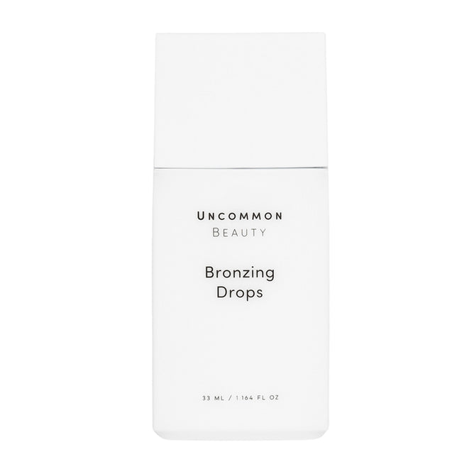A minimalist rectangular white bottle labeled Uncommon Beauty Bronzing Drops in black text holds 33 mL (1.16 fl oz), delivering a sunkissed, post-vacation glow.
