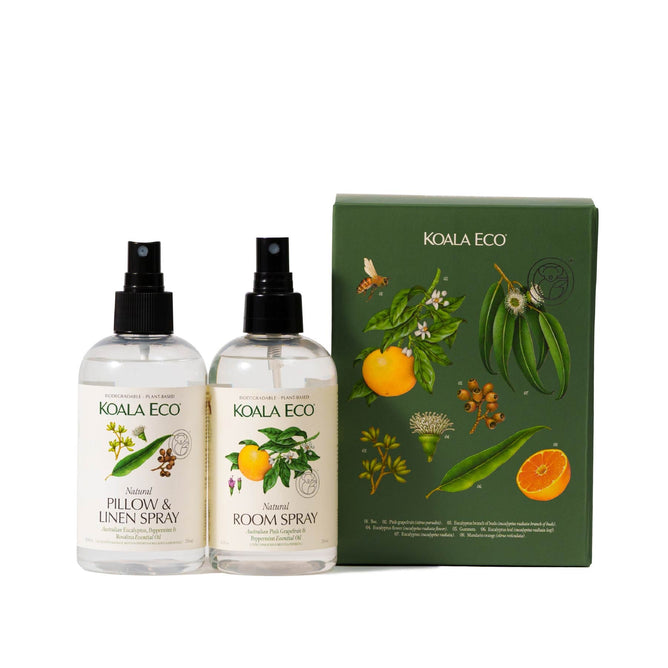 Two spray bottles from Koala Ecos Aromatherapy Duo rest next to a botanically decorated box, providing a sensory experience inspired by Australias botanicals. The left is a Pillow & Linen Spray and the right is a Room Spray, adorned with citrus and eucalyptus illustrations.