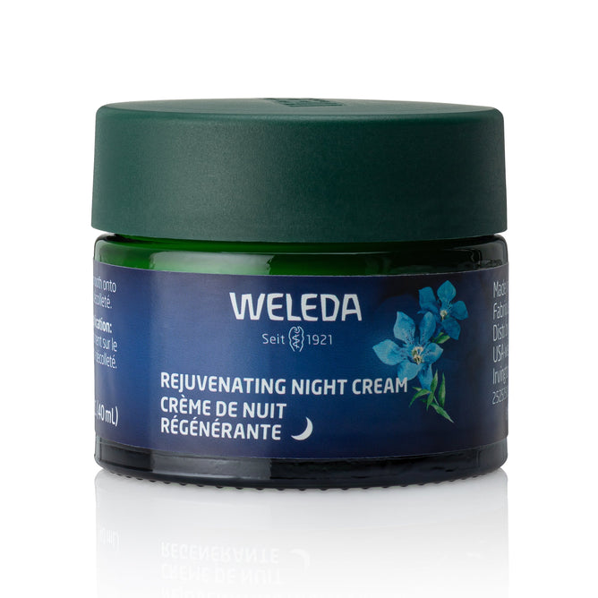 A green jar of Weleda Rejuvenating Night Cream with a dark green lid shows blue gentian and edelweiss on the label. Blue flowers and bilingual text in English and French are visible, all set against a white background.