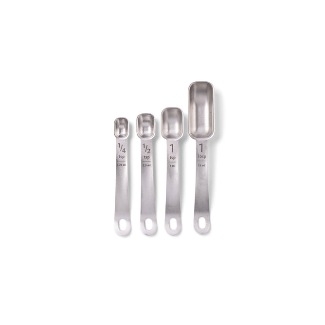 Four Full Circle stainless steel measuring spoons are lined up on a white background. This durable set features etched sizes: 1/4 tsp, 1/2 tsp, 1 tsp, and 1 Tbsp, along with milliliter measurements for precise cooking.