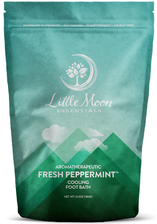 The Fresh Peppermint Foot Soak by Little Moon Essentials offers invigorating relief in 13.5 oz of rejuvenating goodness. Its teal packaging features mountains and text that emphasizes its handmade, natural, planet-friendly, and cruelty-free attributes.