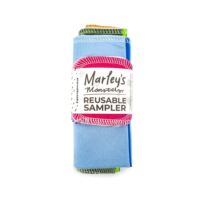 The Reusables Starter Pack by Marleys Monsters is displayed rolled up, showcasing its colorful cotton flannel fabric with visible stitching. Its wrapped in a label featuring the eco-friendly brand name and product type.
