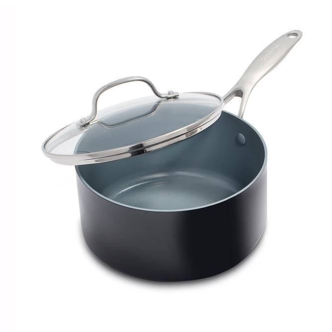 The GreenPan Valencia Pro 2qt saucepan boasts a black exterior with a gray ceramic nonstick interior, stainless steel handle, and partially open glass lid featuring a sleek metal rim. This PFAS-Free cookware is elegantly presented against a white background.