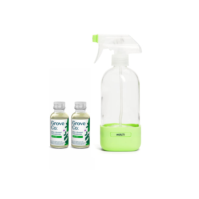 A Grove Co. Glass Cleaner Starter Set features a reusable glass spray bottle with a green base and nozzle labeled Multi, accompanied by two small bottles decorated with green leaf designs, containing wild mint fragrance cleaner concentrate.