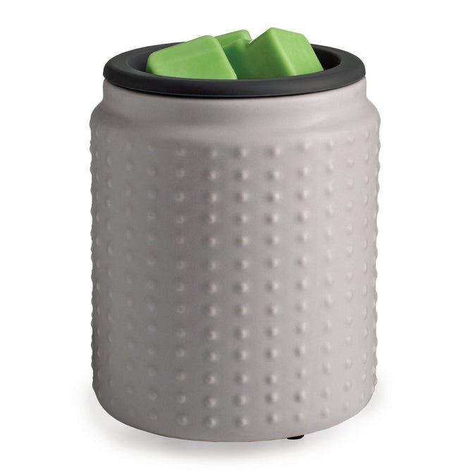 The Wax Warmer with Silicone Dish by Candle Warmers Etc. is gray with a dimpled surface, smooth black rim, and holds two green cube-shaped wax melts. Its cylindrical design adds charm to any room.