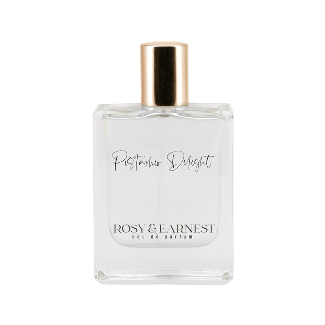 The Pistachio Delight by Rosy & Earnest is a cruelty-free gourmand Eau de Parfum in an elegant rectangular clear glass bottle with a gold cap, showcasing a minimalistic design and transparency.