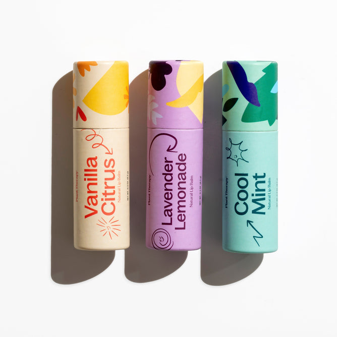 The Love Your Lips Trio Set by Plant Therapy features three vibrant lip balms in upright tubes with natural ingredients. Labels display Vanilla Citrus, Lavender Lemonade, and Cool Mint in orange, purple, and teal abstract patterns—ideal for naturally moisturizing your lips.