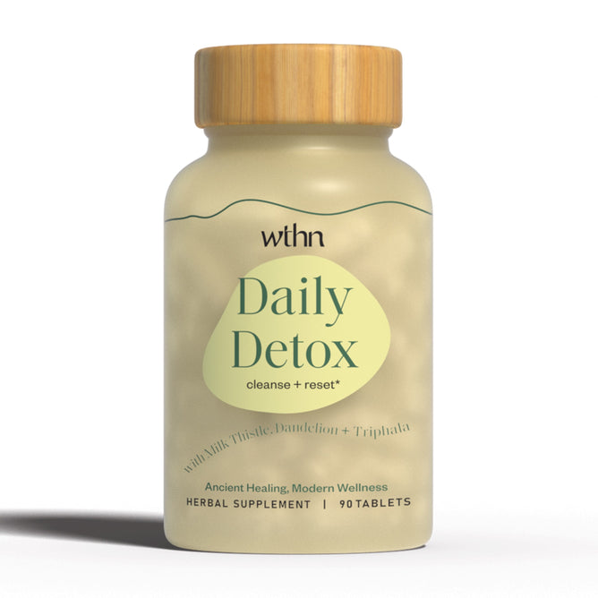 A bottle of WTHNs Daily Detox - Cleanse + Reset herbal tablets, featuring a wooden cap and light green label, contains 90 tablets. The label highlights an organic blend including Milk Thistle, Dandelion, and Triphala to support your detox process.