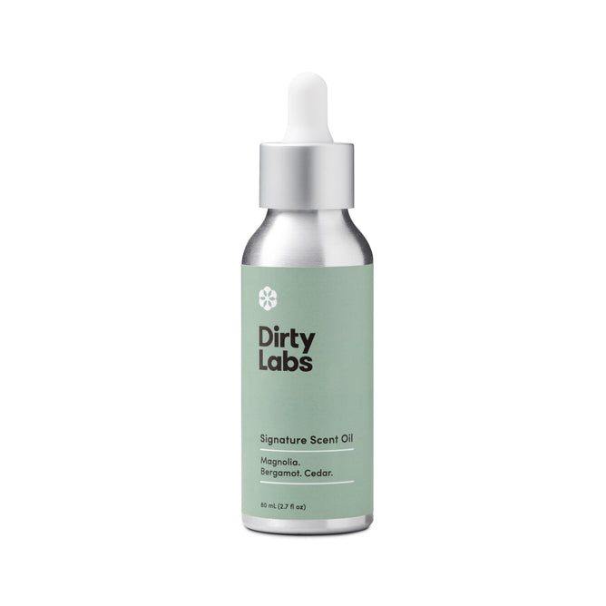 The Dirty Labs Signature Scent Oil + Glass Dropper is a premium metallic bottle with a green label. It showcases magnolia, bergamot, and cedar notes in an 80 mL size and is crafted to be irritant-free.