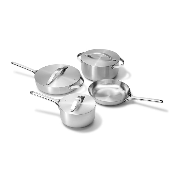The 12-Piece Stainless Steel Cookware Set by Caraway includes a saucepan, frying pan, sauté pan, and stockpot on a white background. Each piece offers non-toxic cooking with corrosion-resistant surfaces, matching lids, and long handles for safe handling.