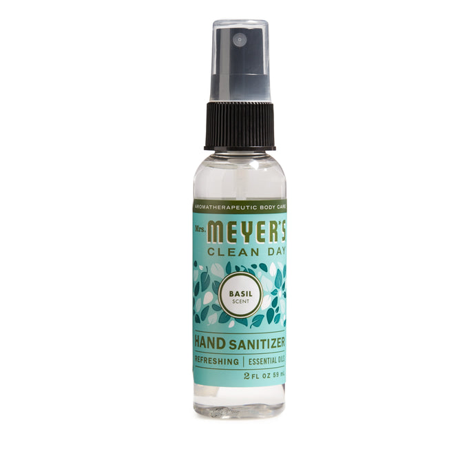 A 2 fl oz bottle of Mrs. Meyers Hand Sanitizer features a refreshing basil scent, decorated with leaf graphics, and contains 62% ethyl alcohol. It has a clear cap over the spray nozzle with a turquoise and white design.