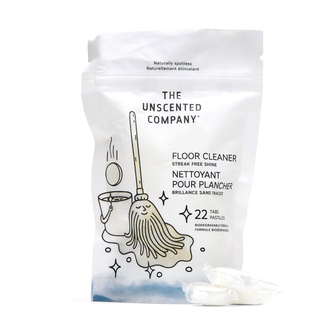 The Unscented Company Floor Cleaning Tabs come in a white stand-up pouch with a smiling mop illustration, offering streak-free cleaning with 22 water-soluble, recyclable tabs. Two white tablets are displayed in front.