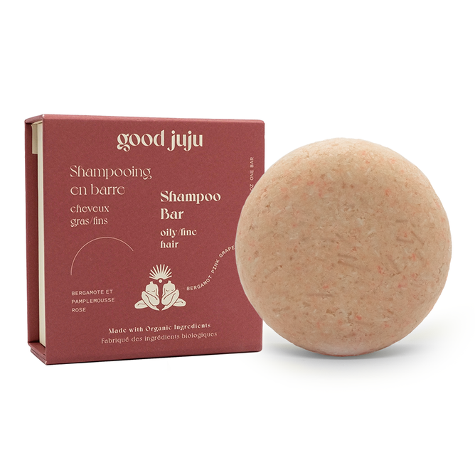 A round Volumizing Shampoo Bar for Oily/Fine Hair by Good Juju Body & Home sits next to a maroon box with white text. The packaging features elegant illustrations of bergamot and pink grapefruit, highlighting organic botanicals for oily and fine hair.