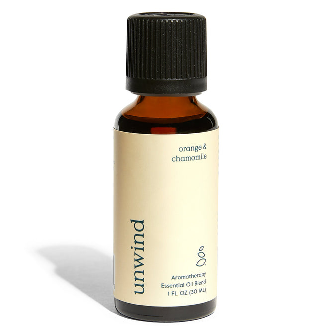 The Unwind Essential Oil Blend by Grove Co. features orange and chamomile in a small brown bottle with a minimalist beige label and sleek black cap, perfect for aromatherapy against a white backdrop.