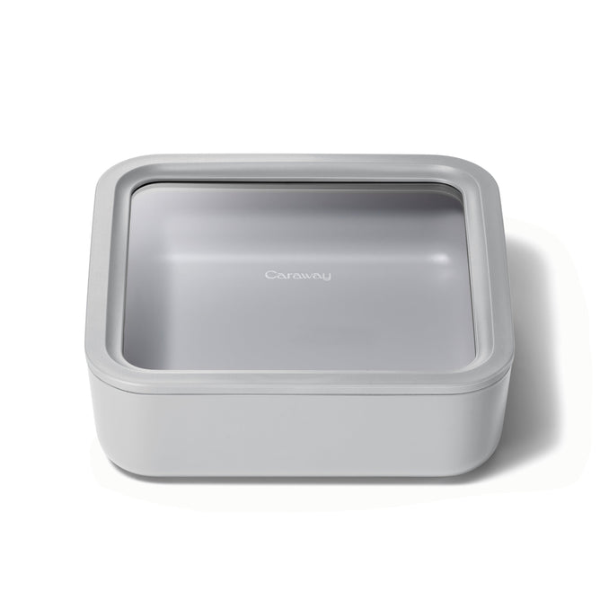 The Large Glass Food Container by Caraway is a square, light gray storage solution featuring a transparent lid with the brand label. Its ceramic-coated glass design is sleek and minimalist, ensuring non-toxic and ideal kitchen use.