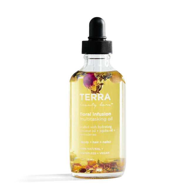 The Floral Infusion Multitasking Oil from Terra Beauty Bars comes in a clear glass bottle with a black dropper cap, enriched with natural oils and flower petals to nourish body, hair, and nails. Its label highlights its vegan and natural formula.