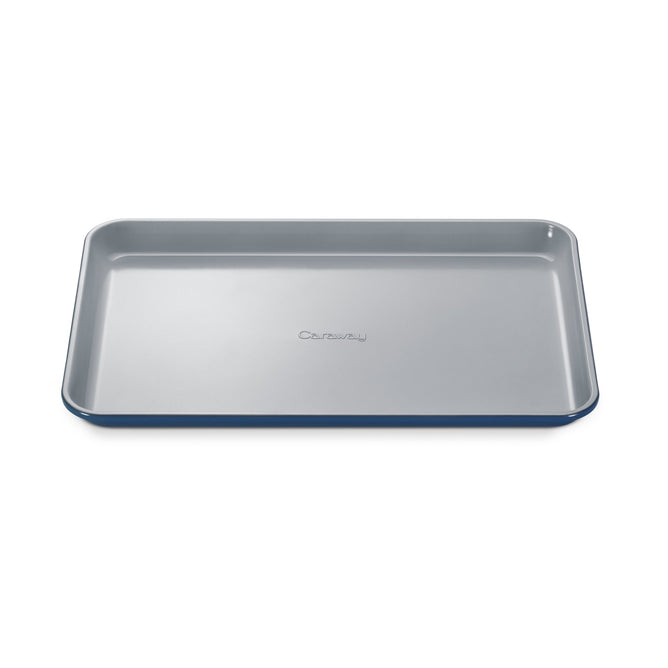 A blue Medium Ceramic Baking Sheet by Caraway, featuring slightly curved edges and the brand name embossed in the center, is set against a white background. Its non-toxic ceramic-coated surface ensures healthy baking.