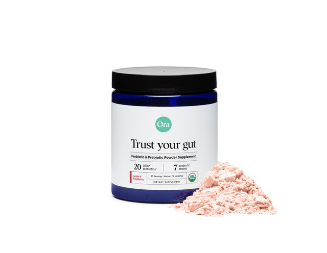 A blue jar labeled Trust Your Gut by Ora Organic sits beside pink powder, showcasing its role as the Organic Probiotics with Prebiotics Powders. With 20 billion probiotics and 7 strains, it supports digestive health through its potent probiotic and prebiotic blend.
