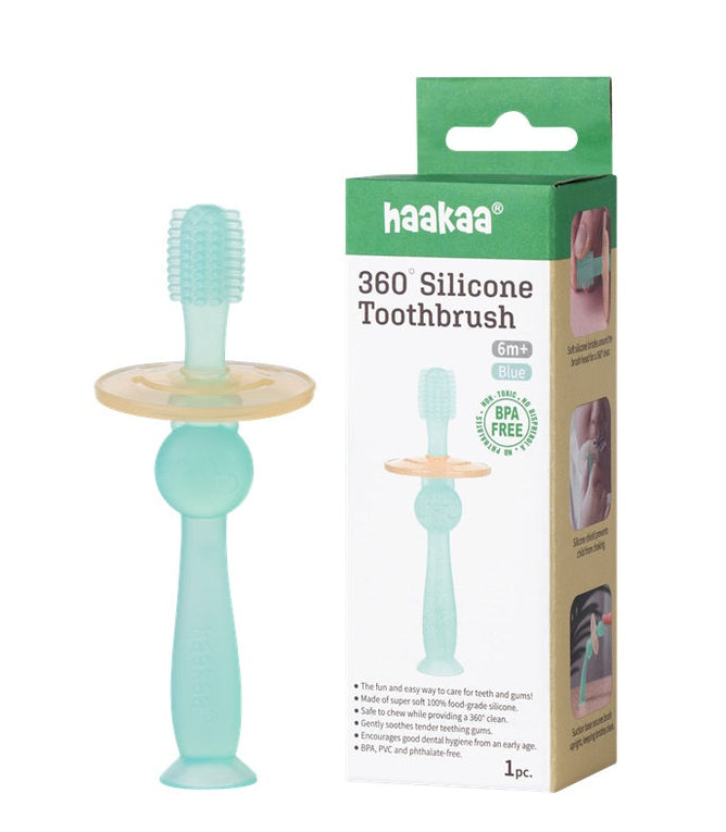 A Haakaa 360 Silicone Baby Toothbrush in teal, suitable for ages 6 months and up, is shown with its packaging. It features soft silicone bristles, a yellow guard, and showcases its BPA-free material and key benefits for childrens dental care on the box.
