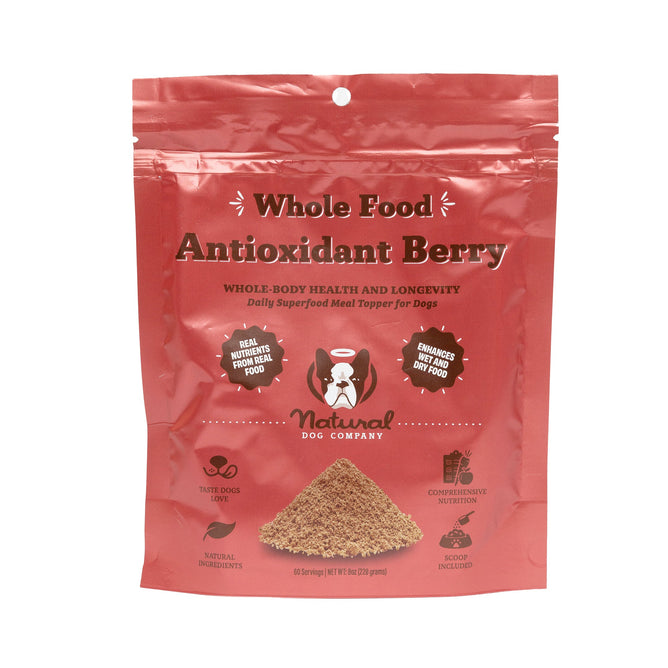 The Antioxidant Berry Superfood Granules by Natural Dog Company come in a red package and are a nutrient-rich meal topper for dogs, promoting health and longevity. They support the immune system with natural ingredients and include a scoop inside.