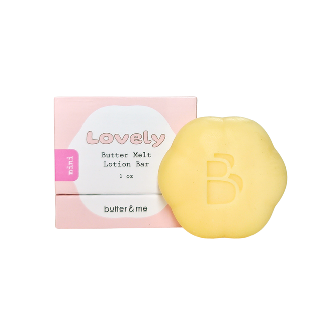 A small, flower-shaped Mini Butter Melt Lotion Bar embossed with B sits beside its pastel pink box reading Lovely Butter Melt Lotion Bar, 1 oz, mini, butter & me in white and black text. This travel-friendly skincare essential is nourishing and eco-friendly.