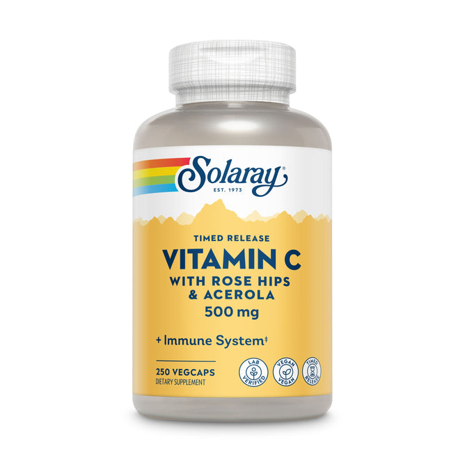 A bottle of Solaray Vitamin C Timed Release with Rose Hips & Acerola, 500 mg, has a yellow label with a rainbow stripe featuring Timed Release and Immune System. It contains 250 vegcaps and includes dietary supplement icons for optimal health support.