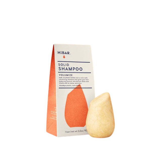 The HiBAR Volumize Shampoo bar, pear-shaped and designed for thin hair, sits next to its off-white rectangular cardboard box with an orange graphic.
