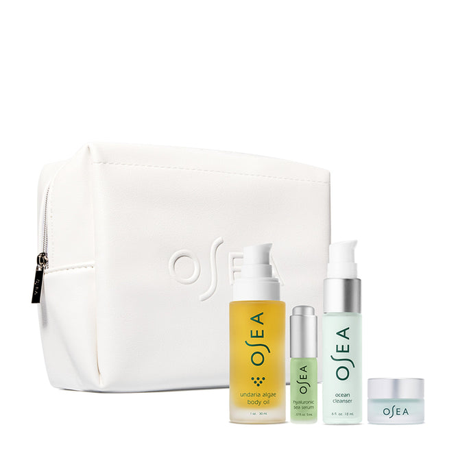 The OSEA Bestsellers Discovery Set is a white cosmetic bag featuring the OSEA logo and includes four skincare essentials: body oil, hyaluronic sea serum, ocean cleanser, and a small jar cream. Each product is designed with minimalist aesthetics in soothing yellow and green tones.