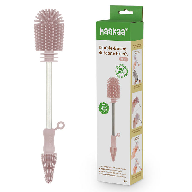 The Haakaa Double-Ended Silicone Cleaning & Bottle Brush features a pink silicone brush with a metal handle and hanging loop, ideal for 360-degree cleaning. Its packaging highlights its BPA-free material, making it essential for bottles, baby gear cleaning, and more.
