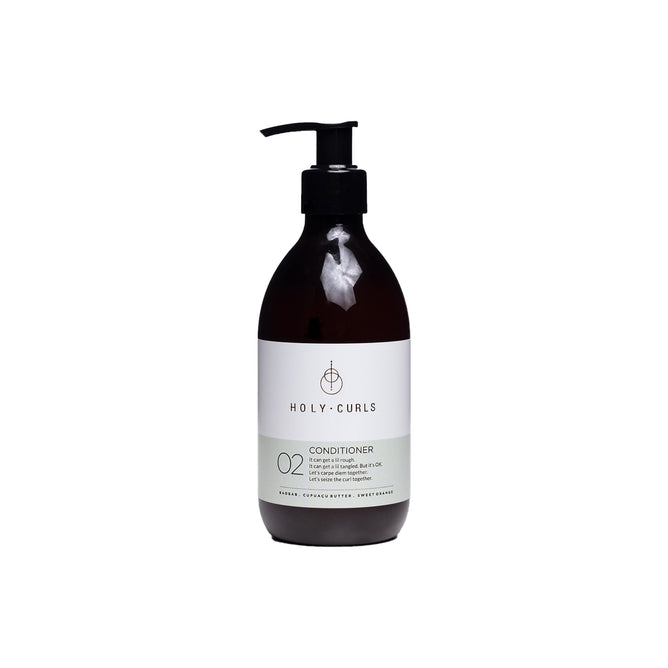 A dark brown pump bottle labeled Holy Curls Conditioner sits elegantly on a plain white background. The minimalist design, featuring a small emblem, highlights ingredients like baobab oil and shea butter, promising to keep your curls hydrated with this moisturizing conditioner.