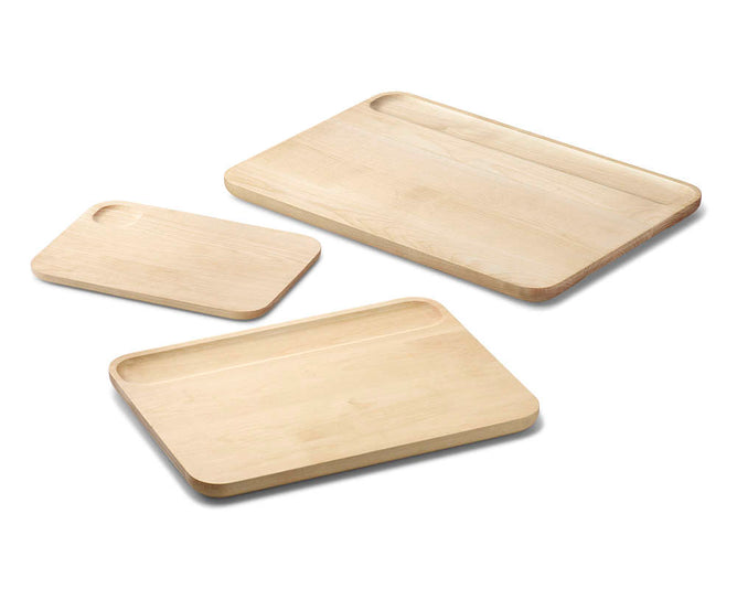 The Caraway Cutting Board Set is crafted from FSC-certified birch wood and includes three non-toxic, rectangular boards with rounded edges. Each board rests on a white background and features a shallow groove on one side.