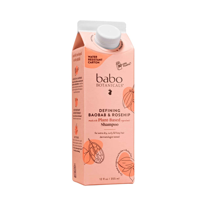 Babo Botanicals Defining Baobab & Rosehip Shampoo in a peach carton, perfect for curly hair, features baobab oil and highlights plant-based and for extra-dry, curly & frizzy hair. Its sturdy white cap enhances a water-resistant, sustainable routine.