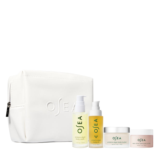 The Bodycare Bestsellers Set by OSEA includes a white toiletry bag with the OSEA logo, featuring four premium body care products—body wash, body oil, body butter, and body scrub—each elegantly packaged and infused with nourishing Undaria Algae for a luxurious travel skincare experience.