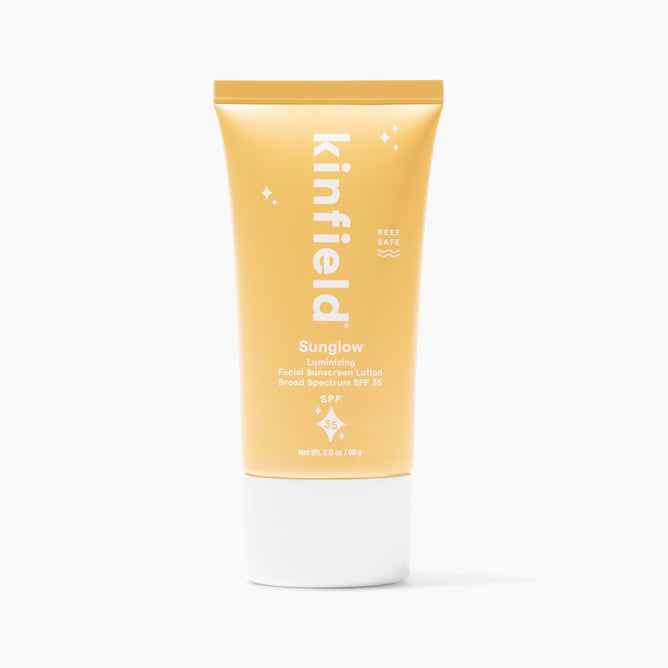 Kinfields Sunglow - SPF 35 is a reef-safe mineral sunscreen in a sleek yellow tube, promising a sun-kissed glow. This luminizing face sunscreen features a minimalist design and stands cap-side down.