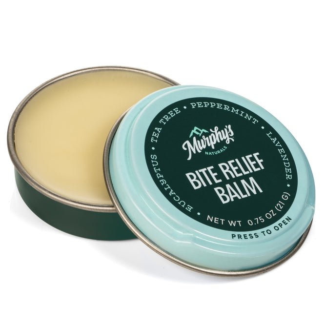 An open round tin of Murphys Naturals Bite Relief Balm reveals the balm inside. The light turquoise lid, adorned with white text, lists ingredients such as tea tree, peppermint, and lavender. Weighing 0.75 oz, this product naturally soothes irritated skin.