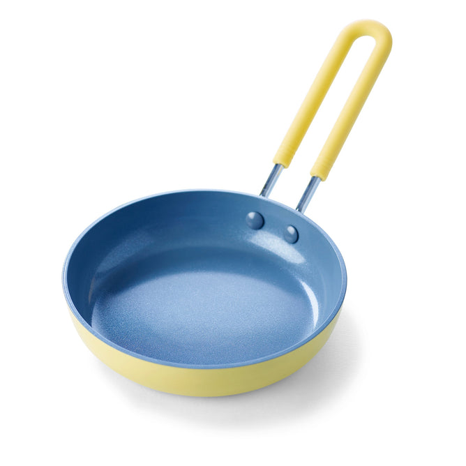 The GreenPan Mini Round Egg Pan features a yellow silicone-coated handle, a blue interior, and a yellow exterior. Made from quick-heating aluminum with Thermolon™ Volt coating, this PFAS-free cookware is designed for efficient cooking.