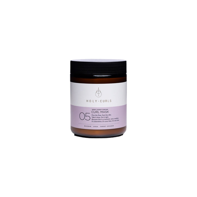 The brown jar of Holy Curls Curl Mask - Deep Conditioner features a white and lavender label with 05, curl mask, and nourish, heal, sweet orange alongside a simple circular logo. The black lid contrasts against the plain white background.