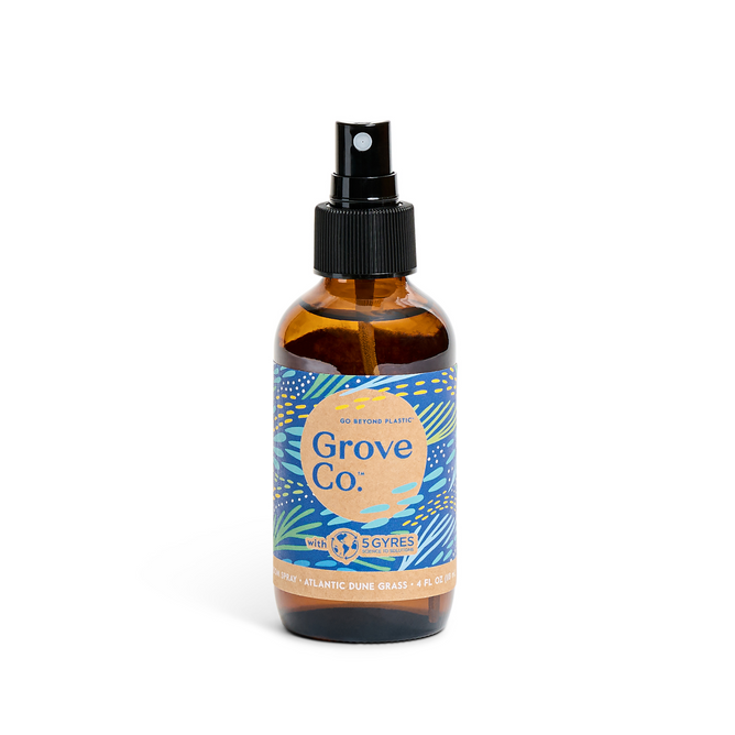 The limited edition Grove Co. Room Spray from the Spring Collection features a brown bottle with a black nozzle and showcases an Atlantic Dune Grass scent, highlighting a commitment to being free from plastic pollution.