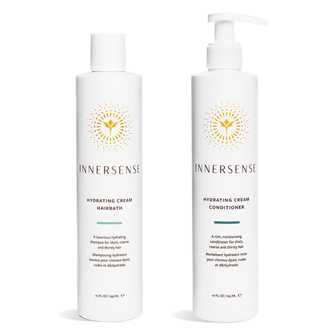 Two white bottles from the Innersense Organic Beauty Hydrating Hairbath & Conditioner Set showcase award-winning formulas. Featuring pumps, elegant gold and black text, a circular logo, and infused with organic ingredients, they highlight Hydrating Cream Hairbath on the left and Hydrating Cream Conditioner on the right.