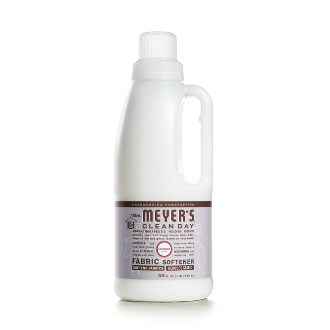 A white 32 fl oz Mrs. Meyers Fabric Softener bottle, featuring a side handle and brown label with white text, showcases its essential oil blend for softening fabrics and reducing static.