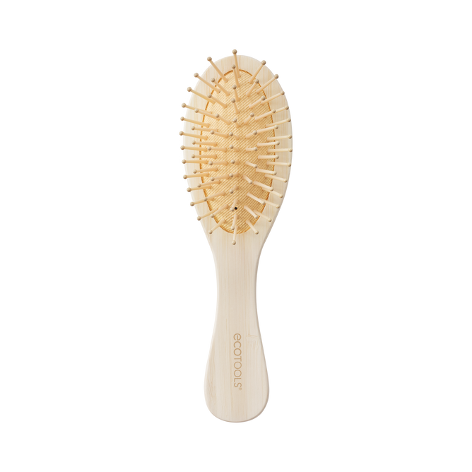 The EcoTools Eco Mini Shine Brush, crafted from 100% renewable bamboo in beige, features a curved handle and widely spaced bristles for gentle detangling. The handle displays the EcoTools logo, and the brush is elegantly showcased on a plain black background.