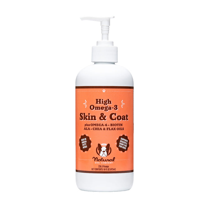 A 16 fl oz (473 ml) bottle of Natural Dog Companys Skin & Coat Oil, featuring Omega-3 and Omega-6, biotin, ALA, chia, and flax oils. Made from 100% natural ingredients with a convenient pump dispenser. The label includes a dog and cat image.