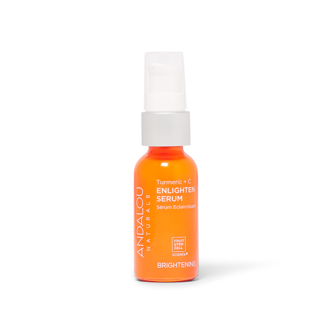 Andalou Naturals Brightening Turmeric + C Enlighten Serum, in an orange bottle with a white pump cap, highlights its vitamin C and Fruit Stem Cell Complex. The label promotes its luminous properties against a plain white background.