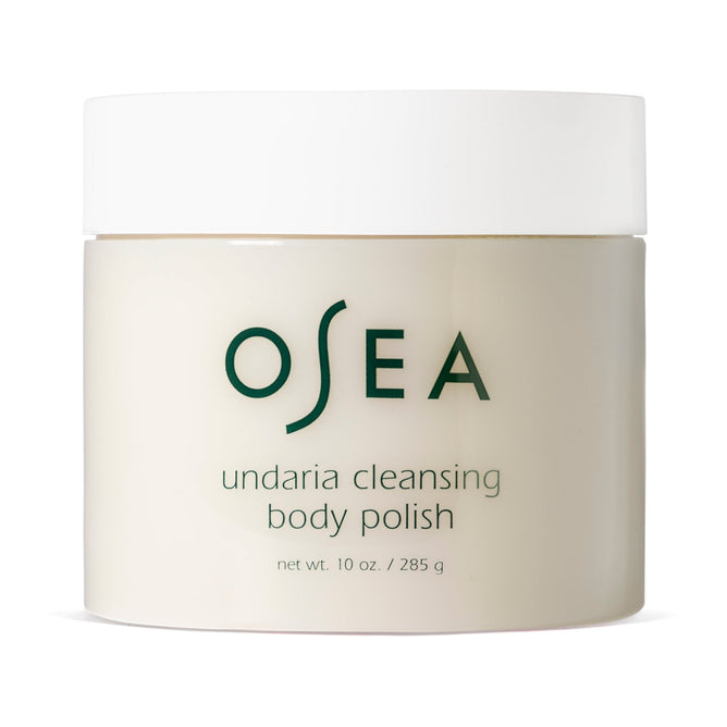 A beige cylinder with a white lid, labeled OSEA Undaria Cleansing Body Polish, 10 oz/285 g in green text, features Undaria seaweed and AHA for exfoliated, revitalized skin.